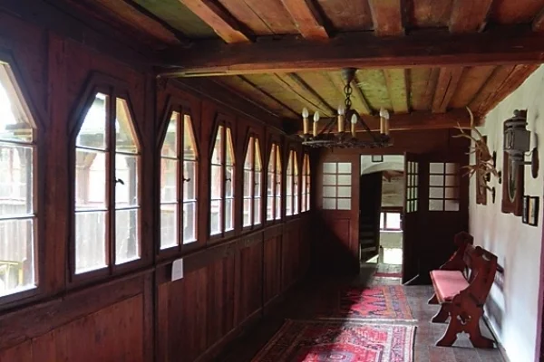 A wooden gallery inside the castle, with windows, benches and an old lantern