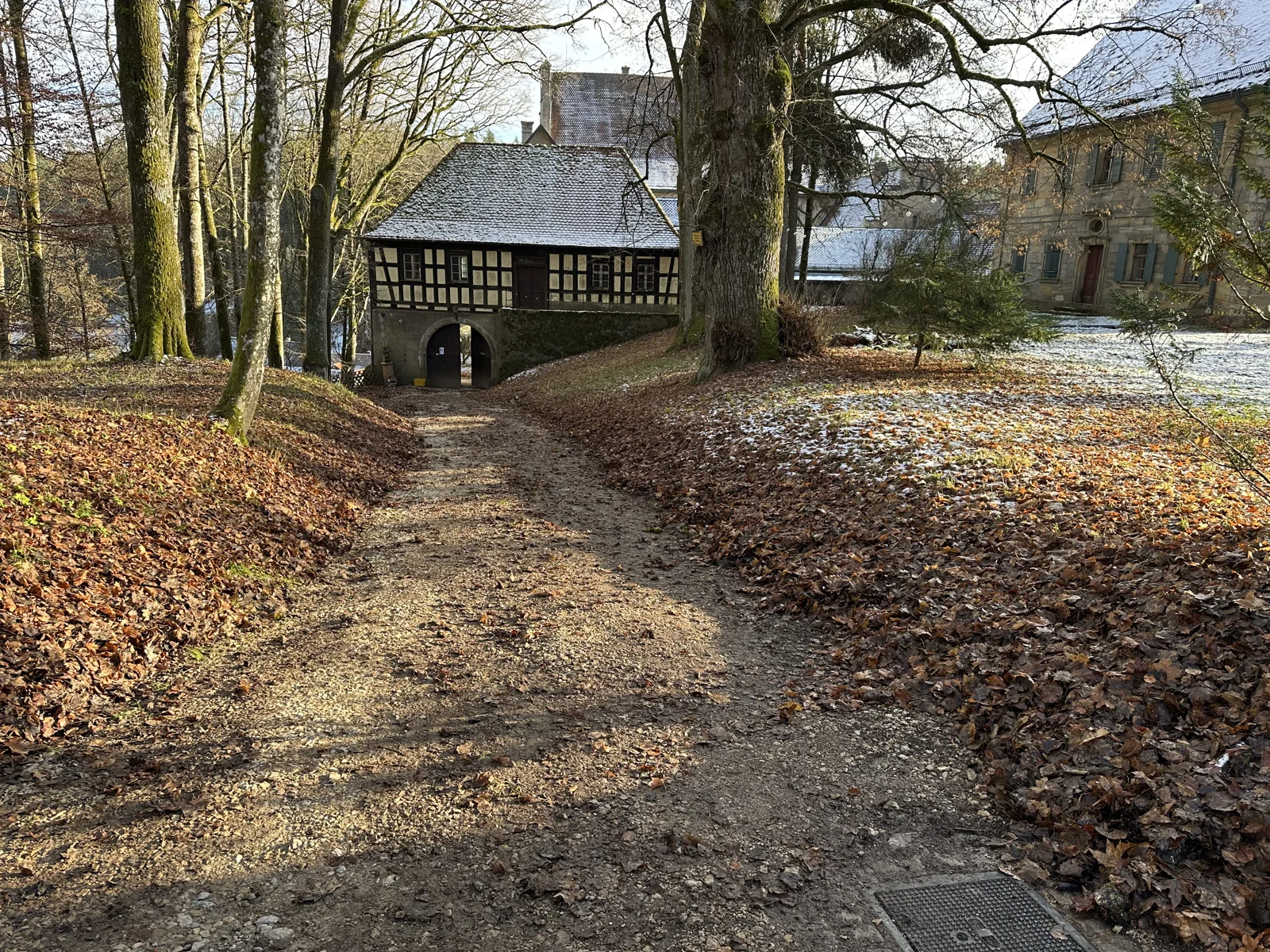 Weg zur Durchfahrt des Torhauses zwischen alten Bäumen